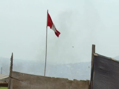 Kenar mahallelerde dalgalanan yırtık bir Peru bayrağı