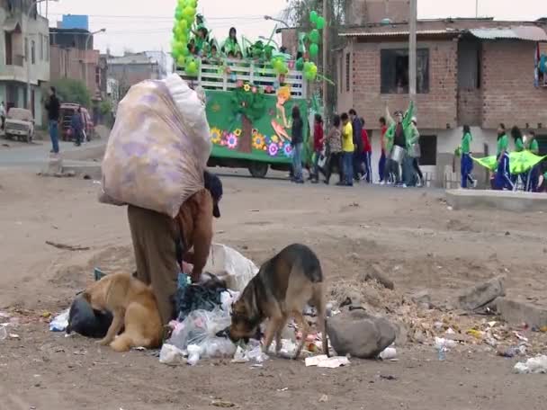 Arka planda geçit töreni olan çöpleri toplayan bir kadın. — Stok video