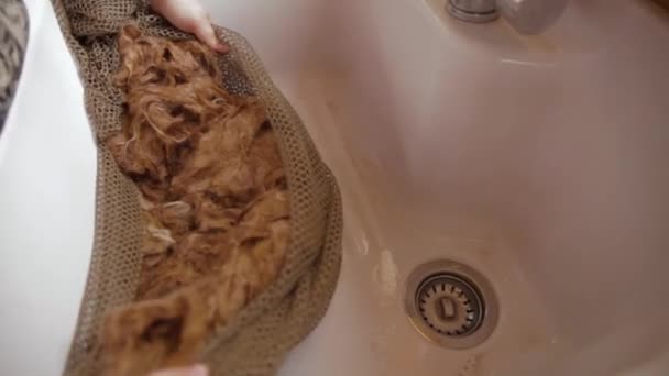 Woman squeezing out dirty water from Alpaca wool — Stock Video