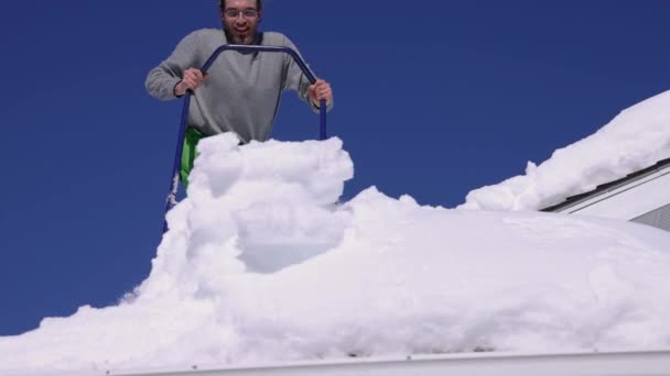 Ta bort nysnö från ett tak under en solig vinterdag — Stockvideo