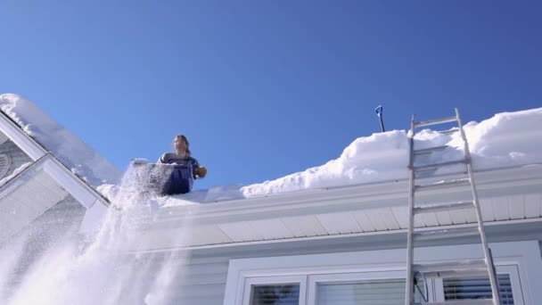 Αφαίρεση φρέσκου χιονιού από μια στέγη σε μια ηλιόλουστη χειμωνιάτικη μέρα — Αρχείο Βίντεο