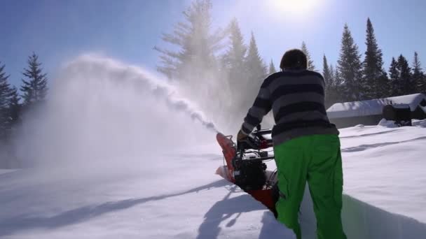 Genç adam kar küreme makinesiyle kar temizliyor. — Stok video
