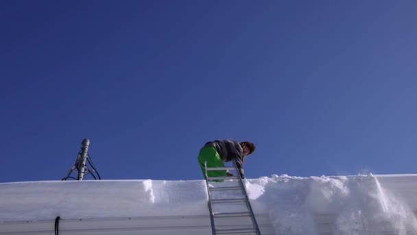 La eliminación de la nieve fresca de un techo en un día soleado de invierno — Vídeos de Stock