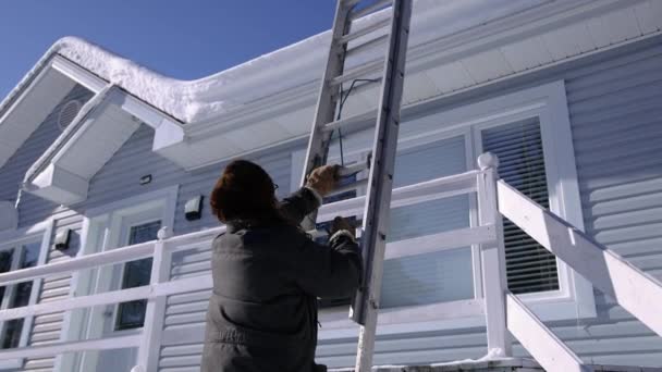 La eliminación de la nieve fresca de un techo en un día soleado de invierno — Vídeos de Stock