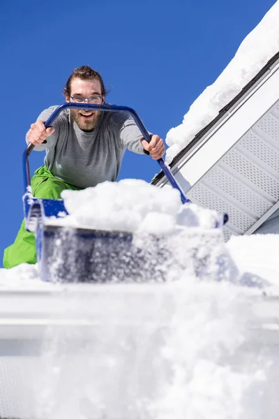 Remover manualmente neve fresca de um telhado — Fotografia de Stock