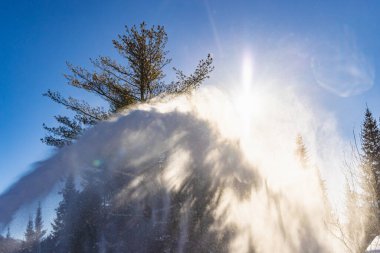 Genç adam kar küreme makinesiyle kar temizliyor.
