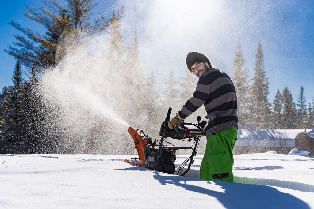 Young man removing snow with mechanical snowplough