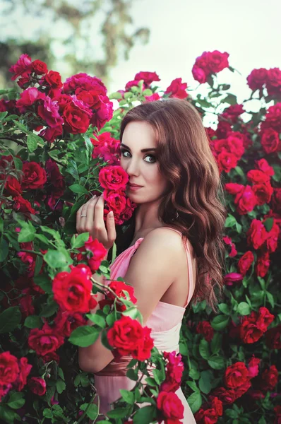 Retrato de una chica morena sobre un fondo de rosas — Foto de Stock