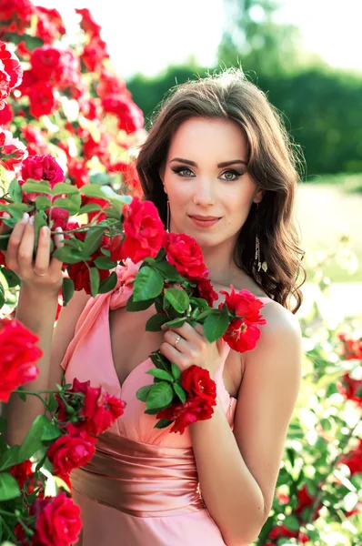 Hermosa chica en rosas en la naturaleza — Foto de Stock