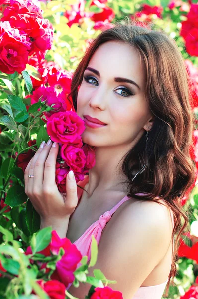 Schöne Mädchen auf einem Hintergrund von Rosen in der Natur — Stockfoto