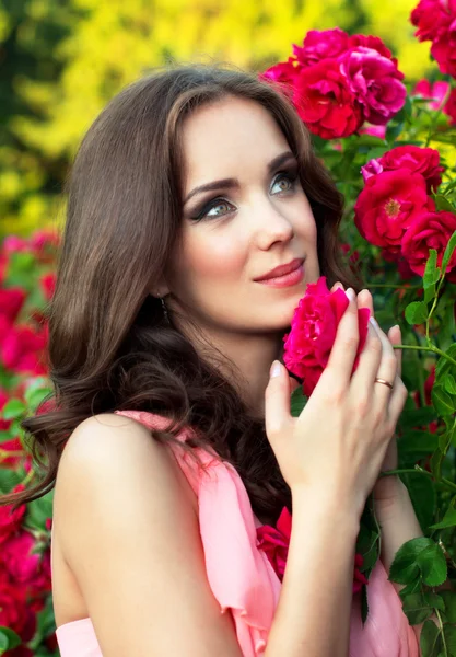 Retrato de cerca de una niña sobre un fondo de rosas —  Fotos de Stock