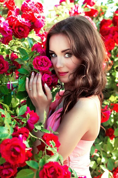 Retrato de una niña sobre un fondo de rosas — Foto de Stock