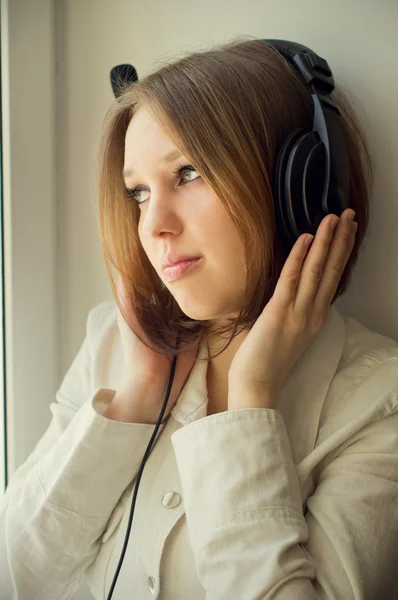 Hermosa chica escuchar música cerca de la ventana —  Fotos de Stock