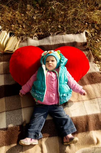 Autumn picnic, a little girl with a toy red heart — Stock Photo, Image