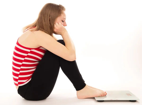 Girl upset more weight, looks at the scales — Stock Photo, Image