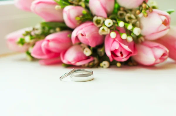 Ring pasgetrouwden liegen over bruiloft boeket — Stockfoto
