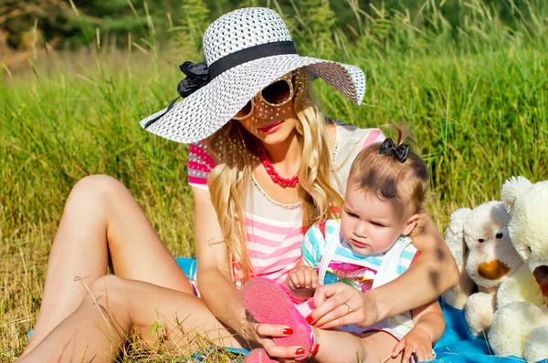 Madre moderna tomando el sol con el bebé en la naturaleza — Foto de Stock