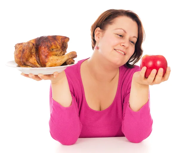 Uma mulher completa é a escolha do que comer frango ou frutas — Fotografia de Stock