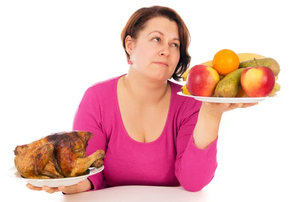 Uma mulher completa é a escolha do que comer frango ou frutas — Fotografia de Stock