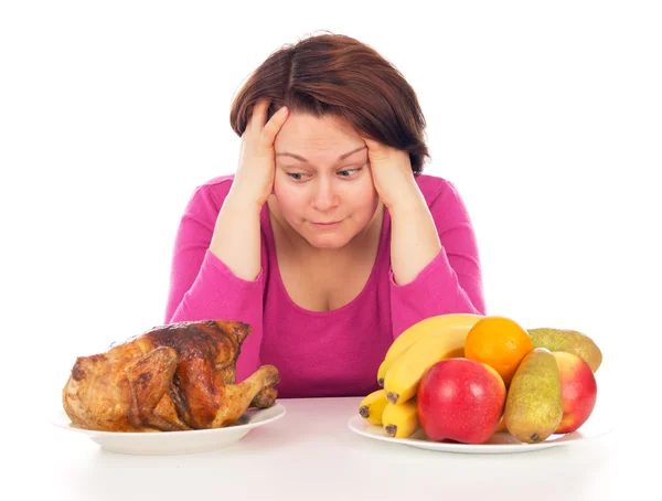 Full woman thinks to eat chicken or fruit — Stock Photo, Image