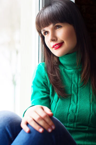 Beautiful girl sitting near the window — Stock Photo, Image