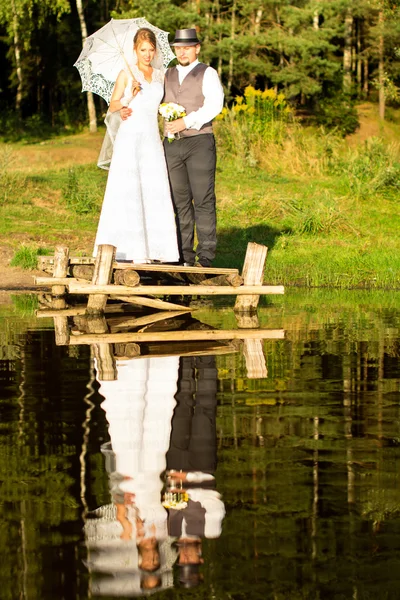 Sposa e sposo sono in piedi su un ponte vicino alla foresta — Foto Stock