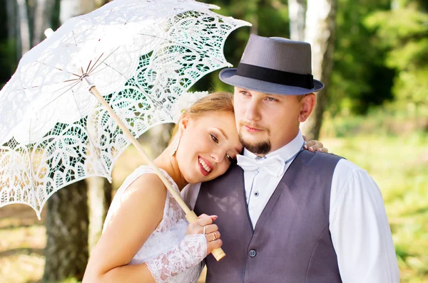 Lyckliga bruden och brudgummen med paraply — Stockfoto