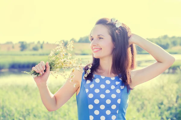 Glückliches Mädchen posiert und Blumen hält — Stockfoto