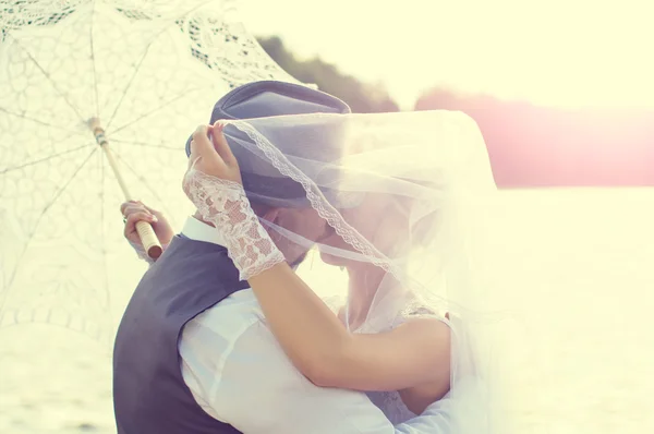 Kiss the bride and groom at sunset — Stock Photo, Image