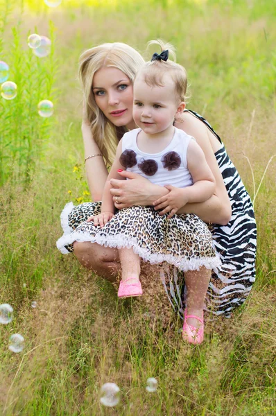 Mãe e filha sobre a natureza de brincar com bolhas de ar — Fotografia de Stock