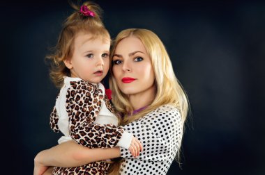 Stüdyoda siyah bir zemin üzerine bir çocukla genç anne