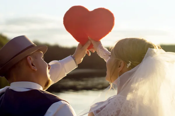 Sonnenuntergang, Braut und Bräutigam halten Herz — Stockfoto