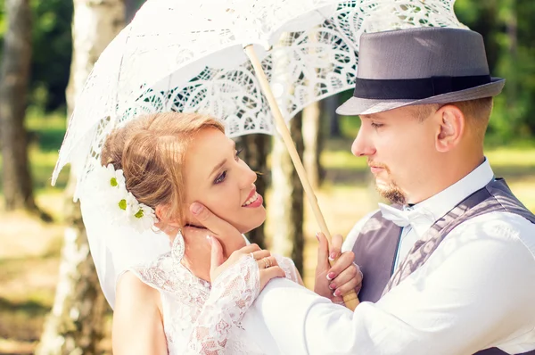 Glückliches Brautpaar mit Regenschirm im Wald — Stockfoto