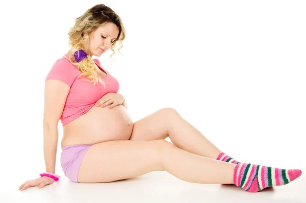 Menina grávida senta-se em um piso branco — Fotografia de Stock