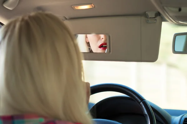 Dziewczyna maluje usta za kierownicą samochodu — Zdjęcie stockowe