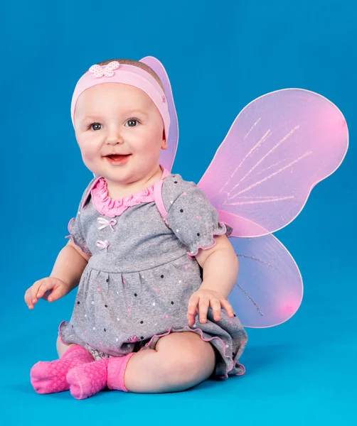 Happy small girl butterfly wings sitting on the floor Stock Image