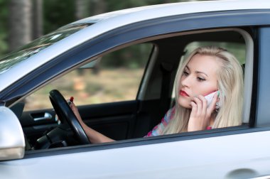 Genç kız dudaklarını boya ve konuşurken bir araba sürüş sırasında