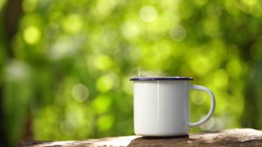 Eski ahşap masa yeşil orman arka planında beyaz mineli kahve fincanı.