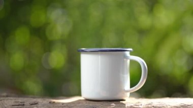 Eski ahşap masa yeşil orman arka planında beyaz mineli kahve fincanı.