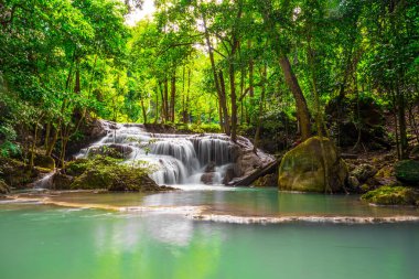 Şelaleler ve balıklar Erawan Ulusal Parkı 'ndaki zümrüt mavi sularda yüzerler. Erawan Şelalesi, Kanchanaburi, Tayland 'da bulunan güzel bir şelaledir. Onsen atmosferi. Taze tabiat 4K