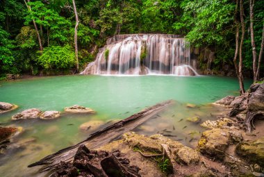 Şelaleler ve balıklar Erawan Ulusal Parkı 'ndaki zümrüt mavi sularda yüzerler. Erawan Şelalesi, Kanchanaburi, Tayland 'da bulunan güzel bir şelaledir. Onsen atmosferi. Taze tabiat 4K