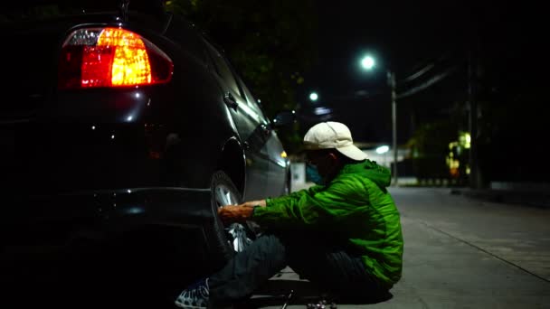 Homem Sênior Usando Uma Máscara Mudar Pneu Beira Estrada Noite — Vídeo de Stock