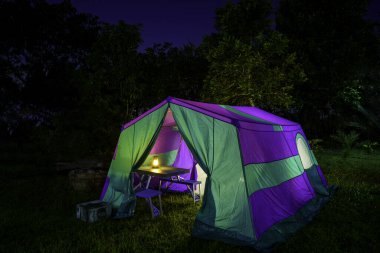 Gece vakti doğa tarafından çevrelenmiş bir ormanda kamp çadırında.