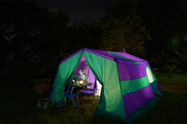 Gece vakti doğa tarafından çevrelenmiş bir ormanda kamp çadırında.