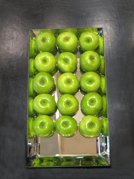 Green apples on mirrored tray — Stock Photo, Image