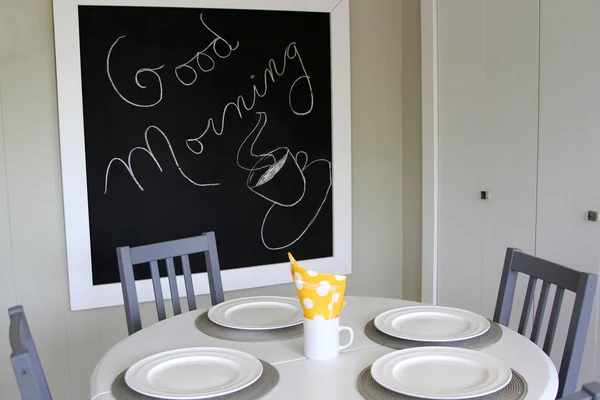 Beyaz mutfak masası, gri sandalye ve yazı tahtası diyor Günaydın — Stok fotoğraf