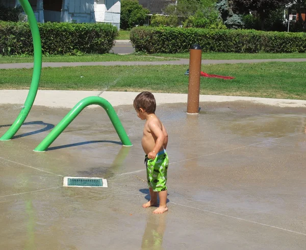 Happy young boy enjoys playing in a water park — Stock Photo, Image