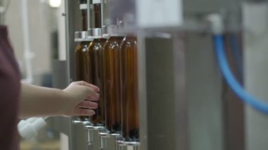 Kahverengi şarap şişelerini konveyörde tıkamak. Ağır çekimde kapat