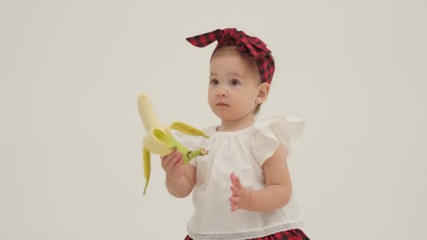 Kleines Mädchen Mit Kariertem Stirnband Bekam Eine Geschälte Banane Zeitlupe — Stockvideo