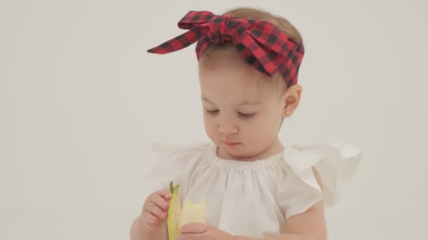 Little Girl Plaid Headband Skirt Eating Big Banana Close Slow — Stock Video
